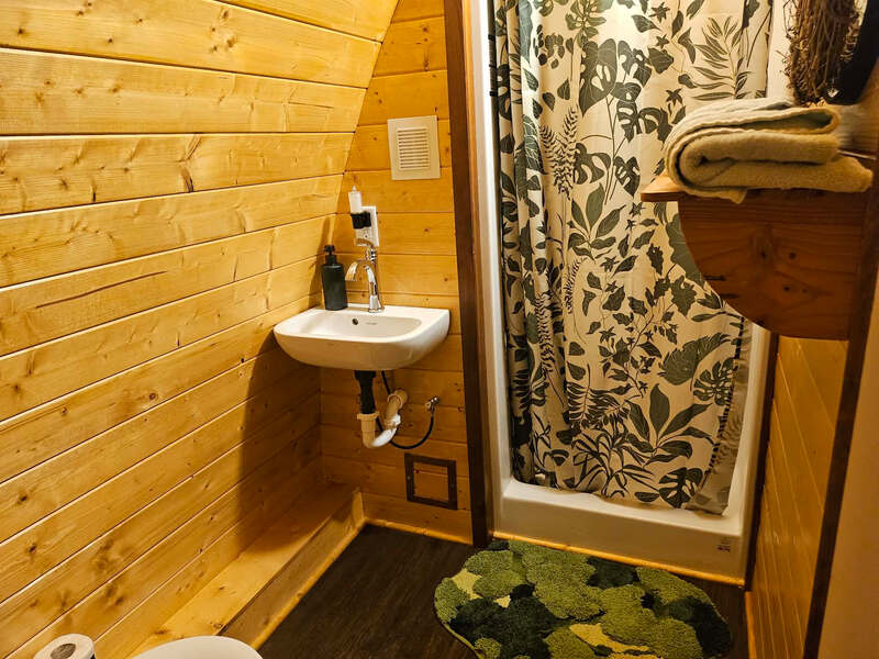 Bathroom with sink and floral shower curtain inside The Little Shire